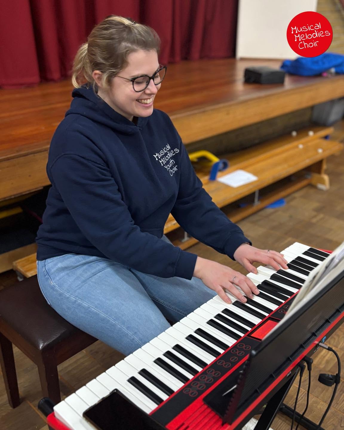 Rebecca Grant, Musical Director of Musical Melodies Youth Choir, smiles as she plays an electronic keyboard during a rehearsal.